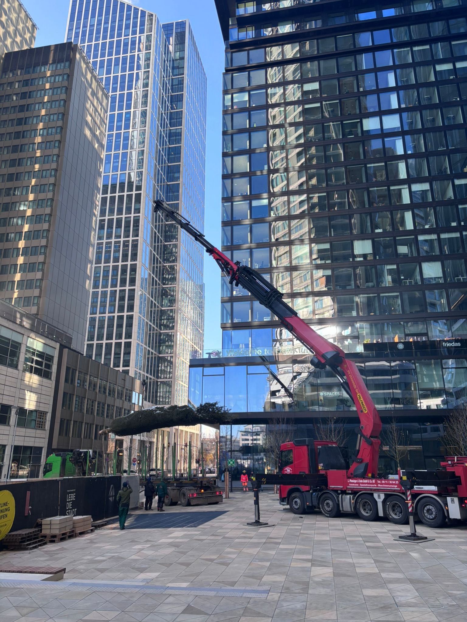 Großer Autokran von Pfenninger hebt Bauteile zwischen Hochhäusern in der Innenstadt.